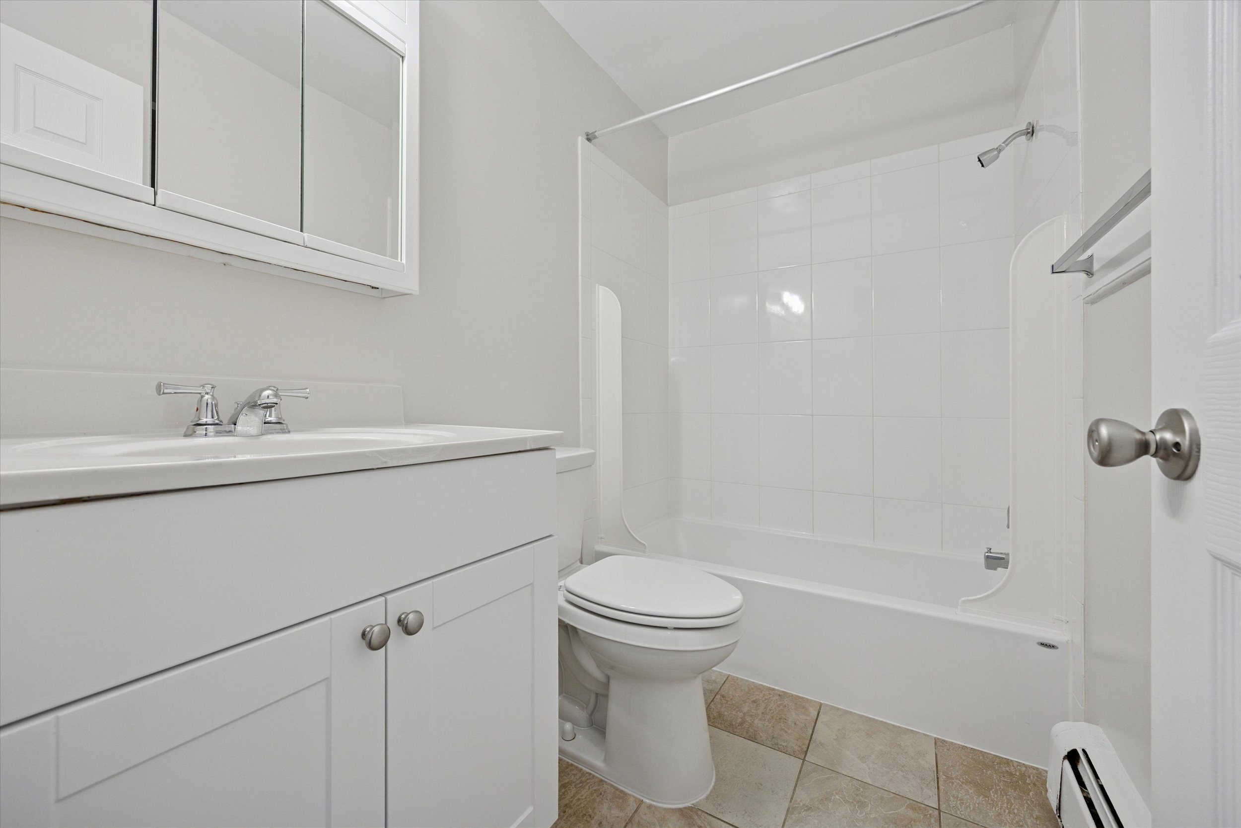A white bathroom with a toilet, sink, and bathtub.